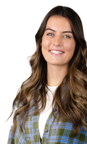 A smiling person with long, wavy brown hair sports a green and blue plaid shirt over a white top, embodying confidence akin to an enterprise SEO agency.