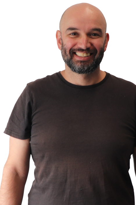 A smiling person with a beard and a shaved head, representing a digital marketing agency, stands confidently in a plain dark t-shirt against a white background.